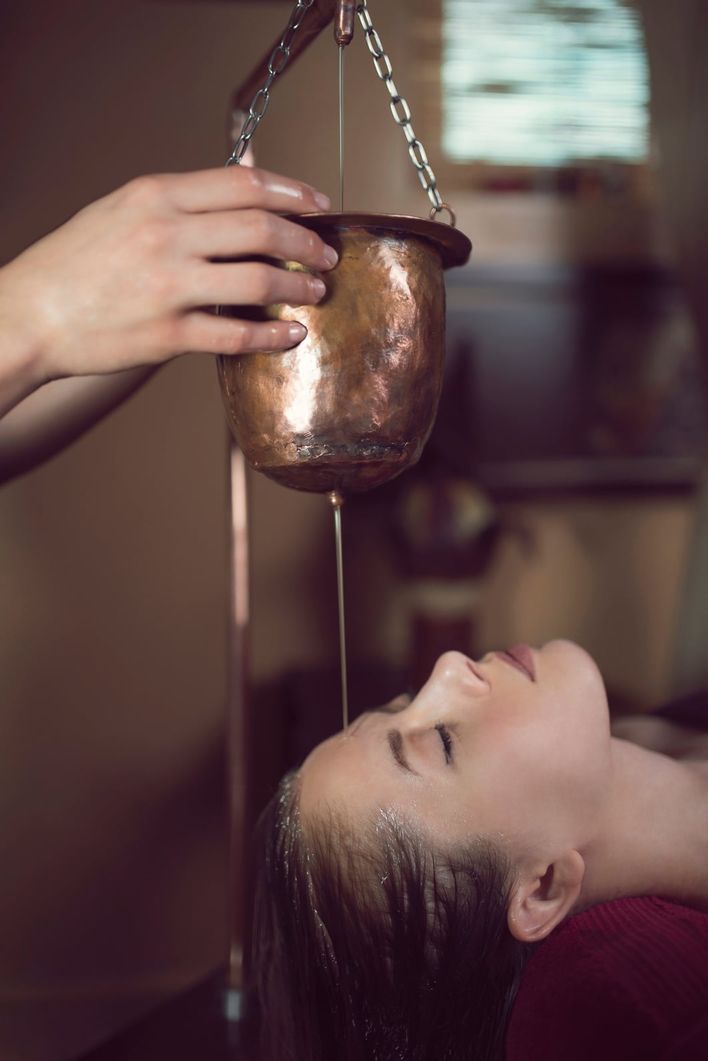 Warm herbal oil flowing onto the forehead during Shirodhara